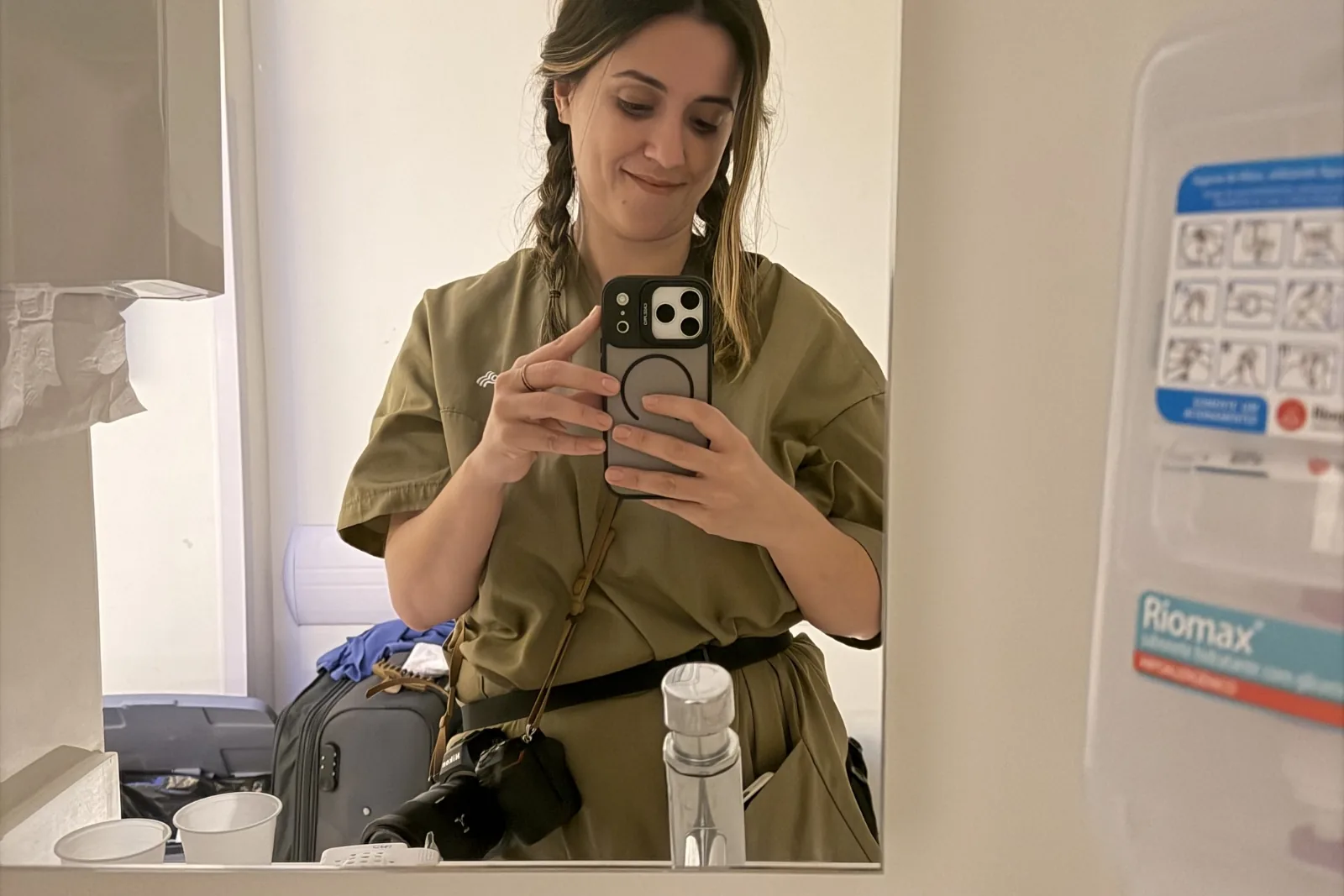 Clara Fernandes diante do espelho com câmera e equipamentos durante um plantão de fotografia de parto