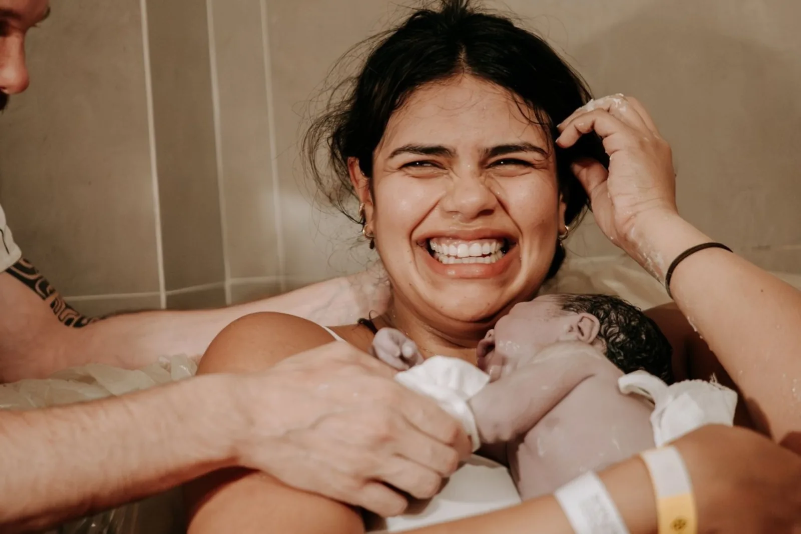 Mãe sorrindo com o bebê no colo durante o primeiro encontro após o parto
