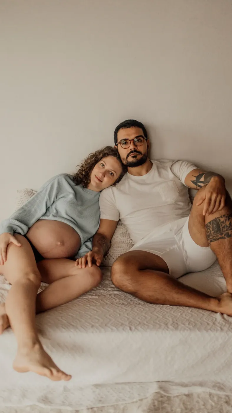 Casal de gestantes sentado na cama