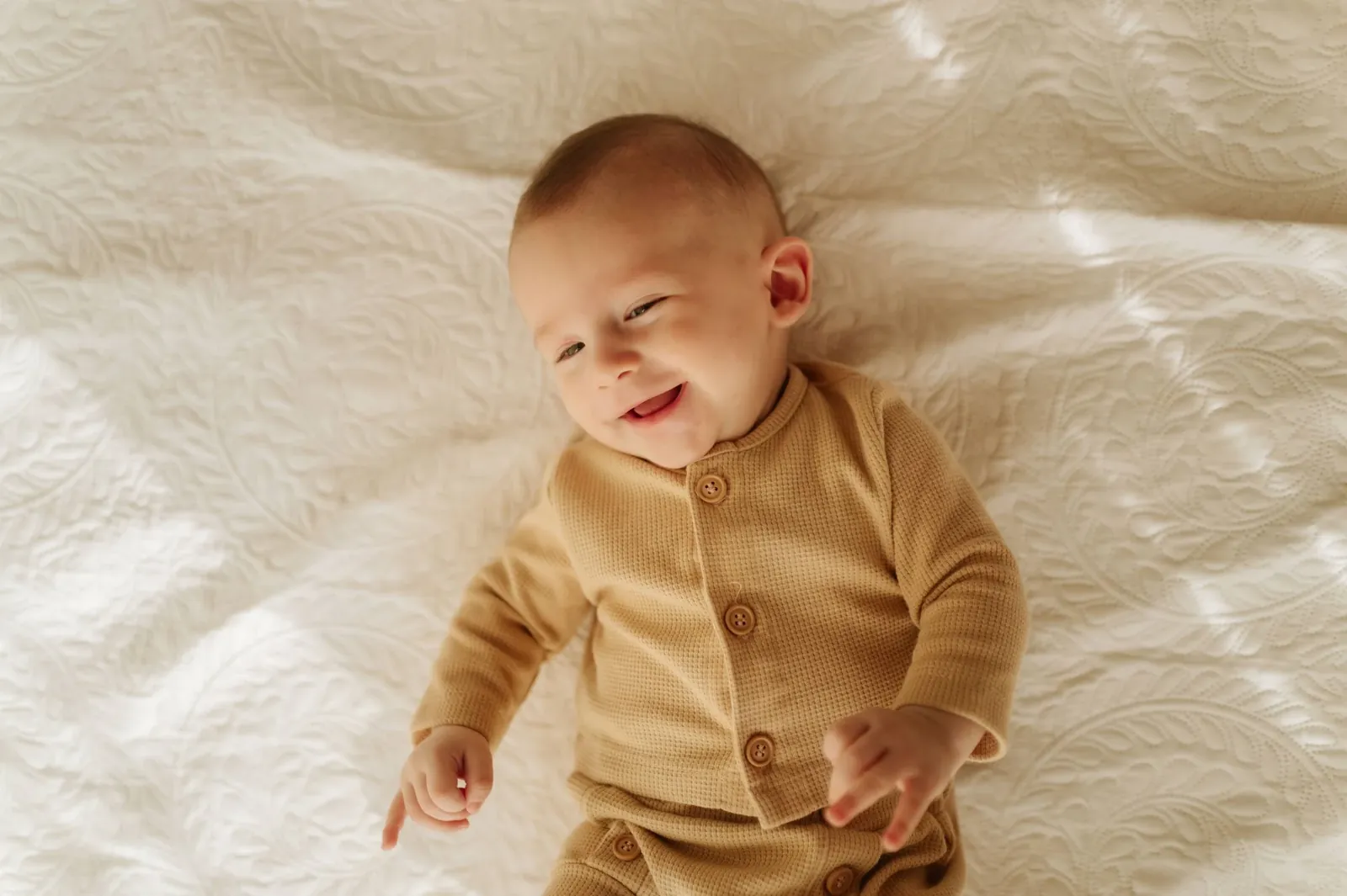 Bebê de três meses sorrindo na cama